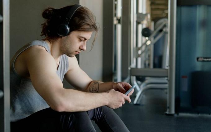 Man met koptelefoon die zijn smartphone gebruikt